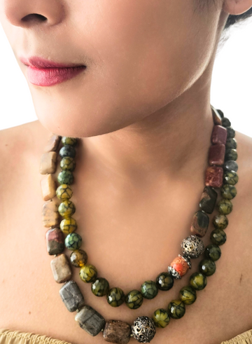 A person wearing a jade and silver medley necklace with flat jade beads and silver carved beads.