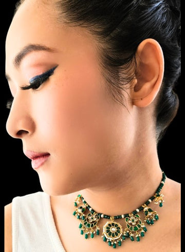 A person wearing a green onyx kundan necklace with pearl accents.