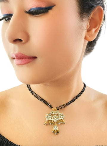 A woman wearing a white kundan lotus pendant necklace with black beads.