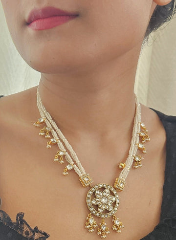A person wearing a traditional golden necklace with intricate designs and small pearls.