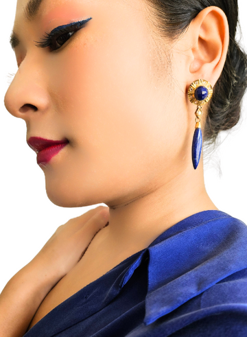 A close-up image of a person wearing blue lipstick and blue earrings with a large blue stone drop and pure silver studs.