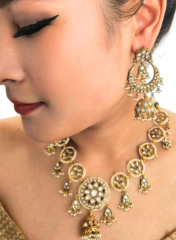 Close-up of a woman wearing an ornate gold necklace and earrings.