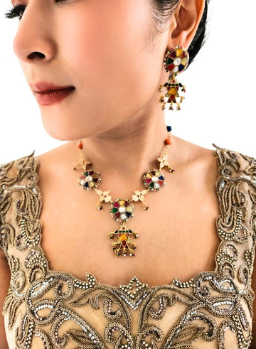 A person wearing a Navrattan necklace with circular elements and a Navrattan fish drop, paired with matching earrings.