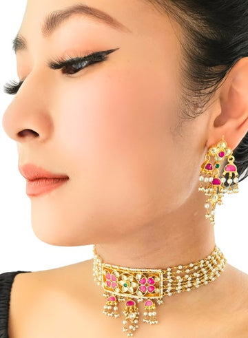 A woman wearing a gold-colored kundan choker and pearl earrings with rhinestone accents.