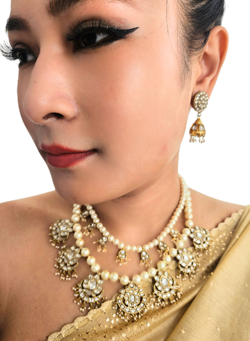 Woman wearing a gold and pearl jewelry set with earrings 