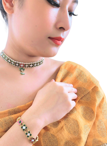Woman wearing a gold saree with jewelry, including a necklace and bracelet.