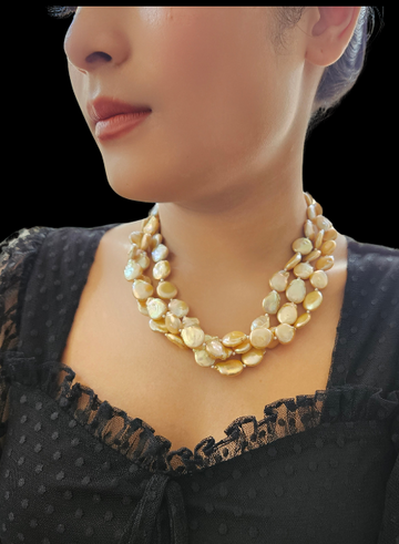 A woman wearing a black dress with a multi-string champagne-colored coin pearl necklace.