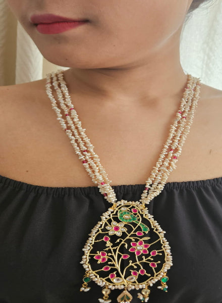 Woman wearing a long beaded necklace with a decorative pendant.