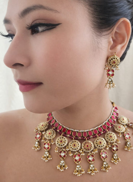 Close-up of a woman wearing an elaborate gold and red jewelry set with earrings and necklace.