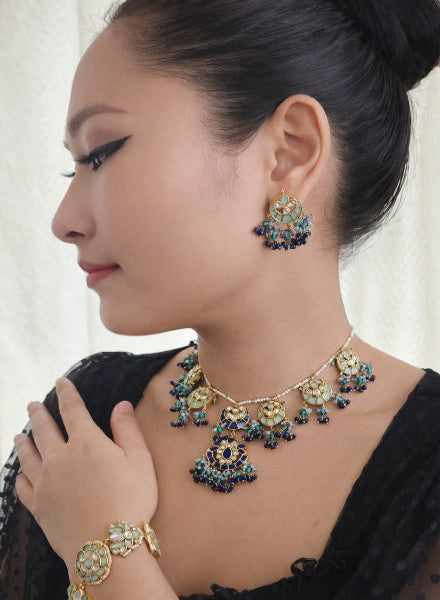 Woman wearing a detailed necklace, earrings, and bracelet 