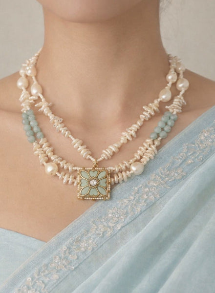 Necklace with pearls and turquoise stones worn by a person in a light blue saree.