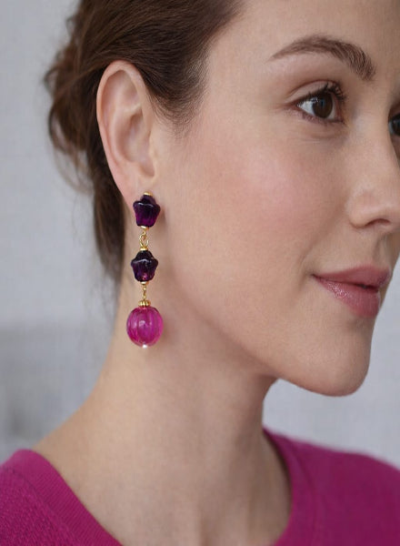 Close-up of a woman wearing a pair of earrings with purple and pink beads.