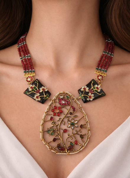 Close-up of a decorative necklace with red and green beads and gold accents.