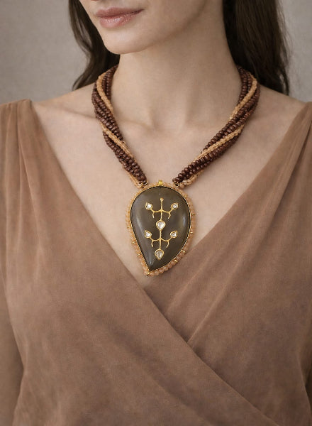 Woman wearing a brown necklace with a large pendant 