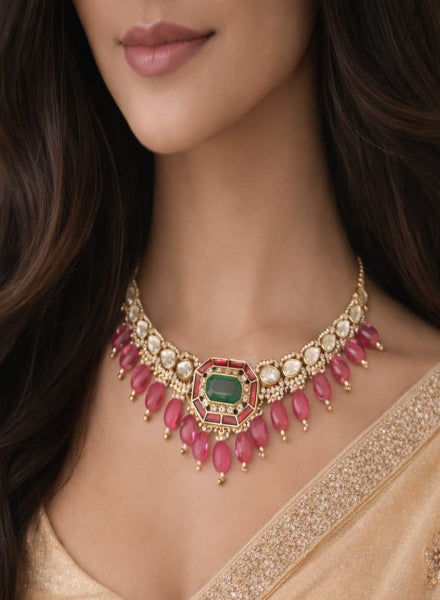 Close-up of a woman wearing an ornate necklace with red and green gemstones.