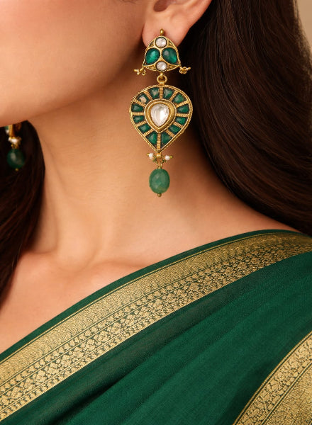 Close-up of a person wearing a green saree with gold border and a matching earring.