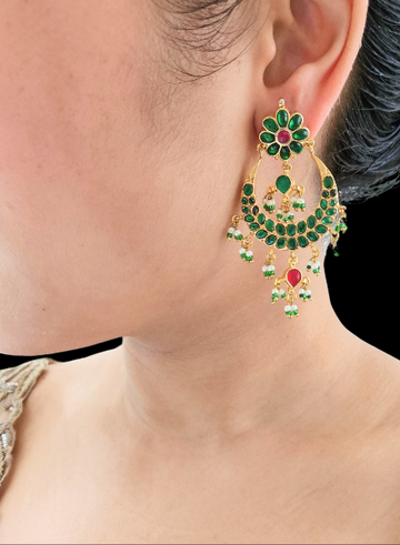 A person wearing a pair of green Chandbali earrings with gold detailing and red accents.